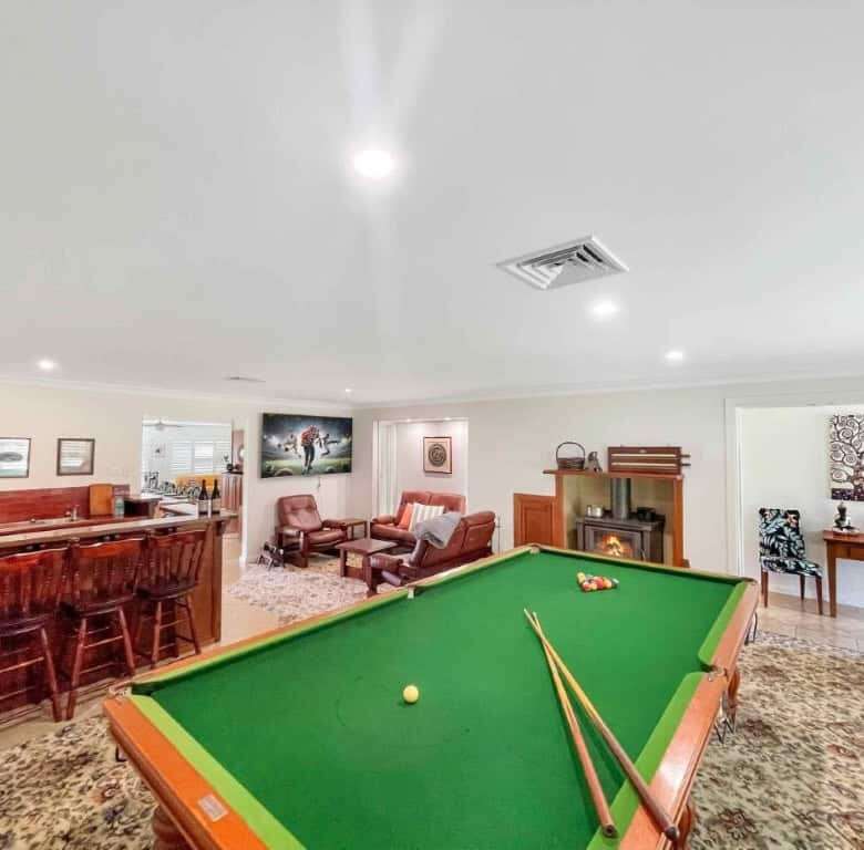 Spacious living room with a pool table, cozy fireplace, and elegant decor at the Vineyard Estate in.