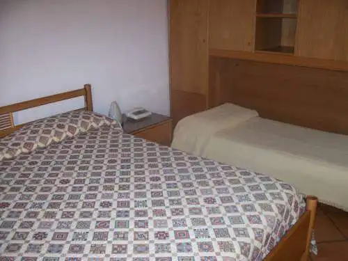 Hotel room with two beds and wooden furniture near Lake Viverone, Piverone, Italy.