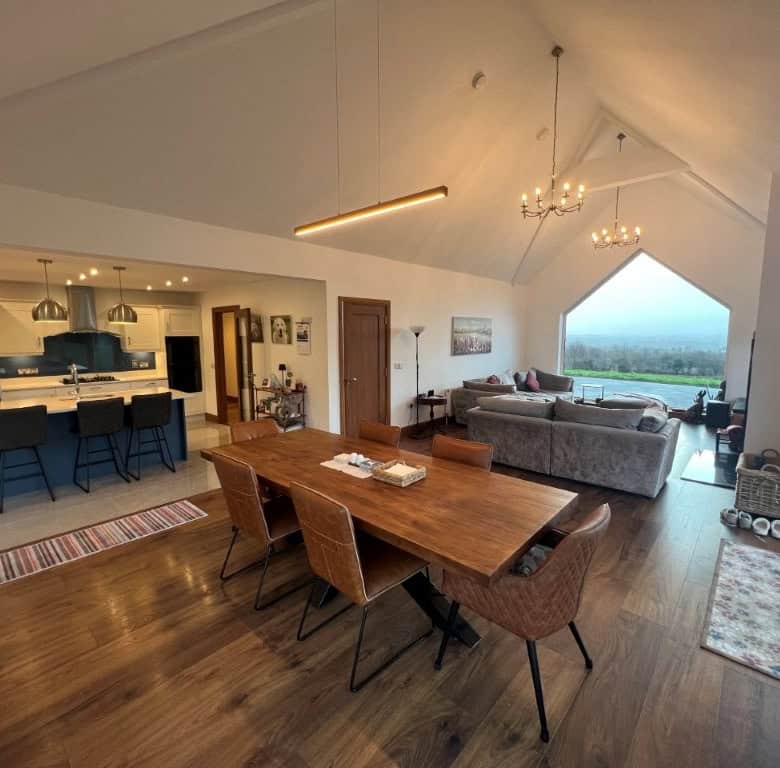 Interior view of a spacious, modern living and dining area with panoramic countryside views.