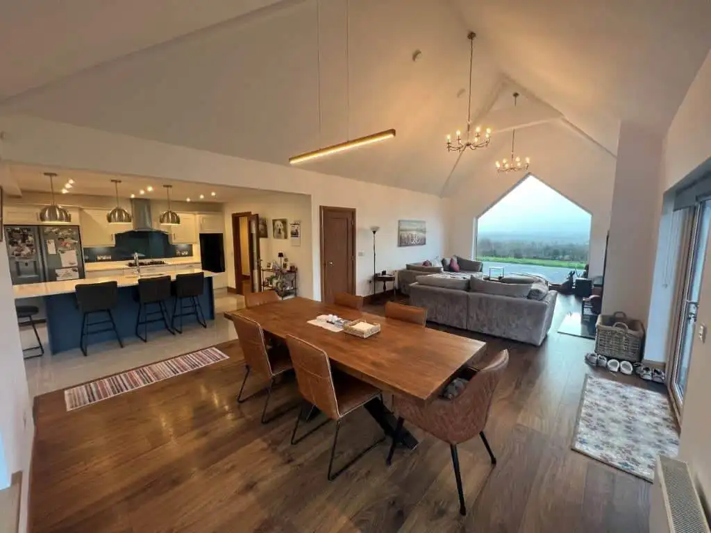 Interior view of a spacious, modern living and dining area with panoramic countryside views.