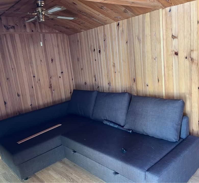 Modern wooden interior with a dark gray sectional sofa in a cozy mobile home.