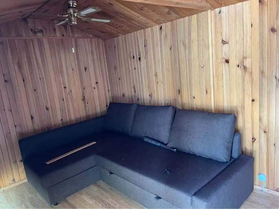 Modern wooden interior with a dark gray sectional sofa in a cozy mobile home.