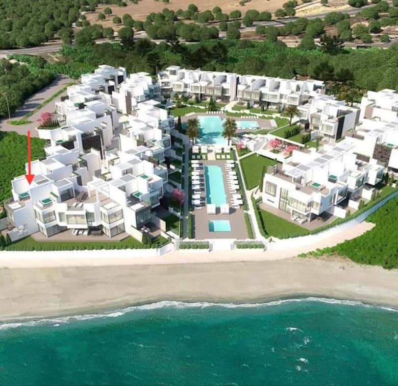 Luxury beachfront townhouses in Estepona West with pool and lush gardens.