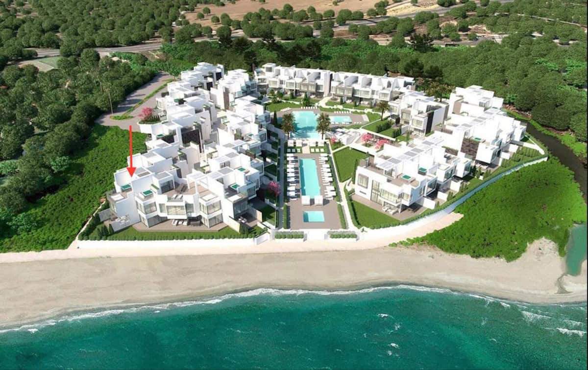 Luxury beachfront townhouses in Estepona West with pool and lush gardens.
