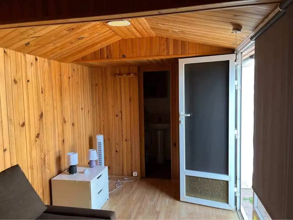 Mobile home interior with wooden walls and ceiling, featuring a door leading to an outdoor space.