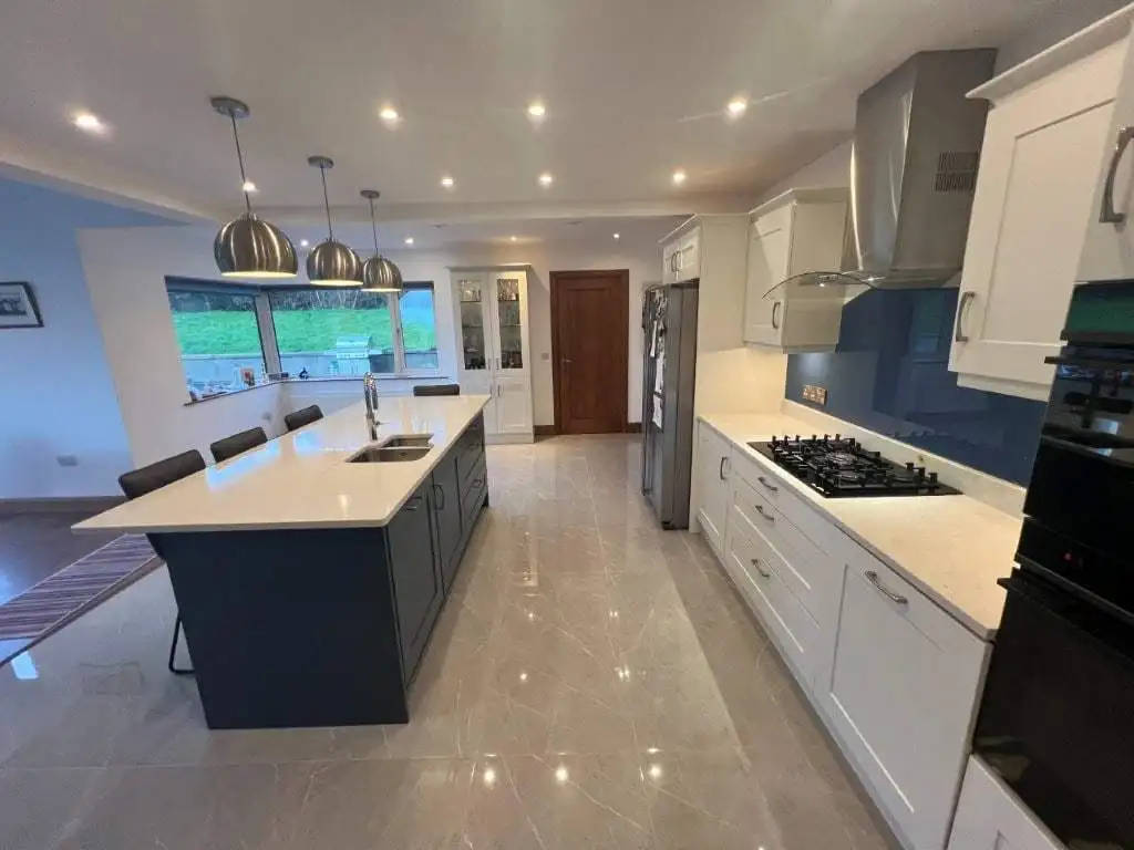 Contemporary kitchen featuring white cabinets, a large island, and modern appliances.