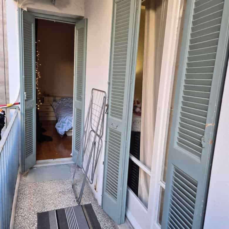 Cozy balcony with shutters overlooking the interior of a city apartment in Kypseli, Athens.