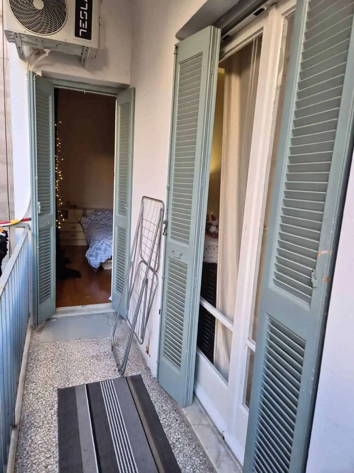 Cozy balcony with shutters overlooking the interior of a city apartment in Kypseli, Athens.
