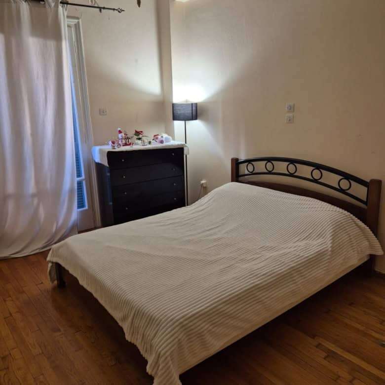Bright bedroom with balcony, simple decor, and wooden flooring in Kypseli, Athens.