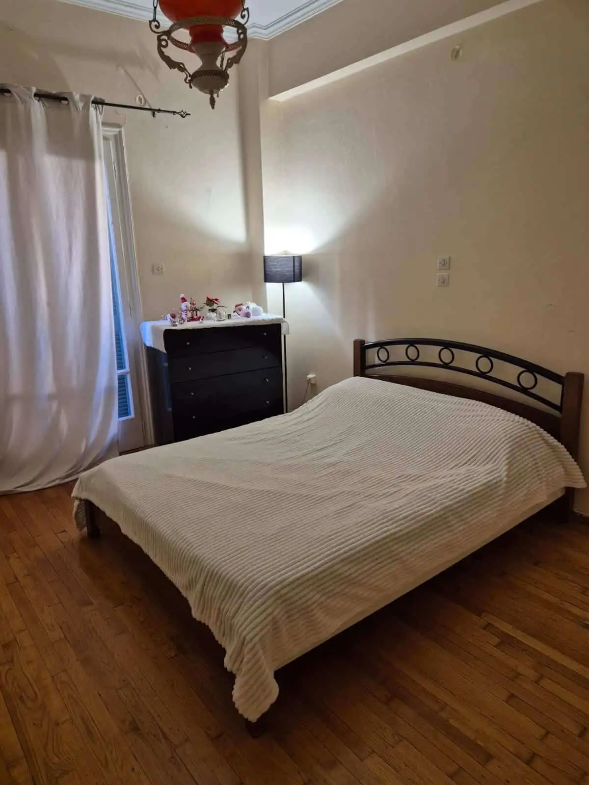 Bright bedroom with balcony, simple decor, and wooden flooring in Kypseli, Athens.