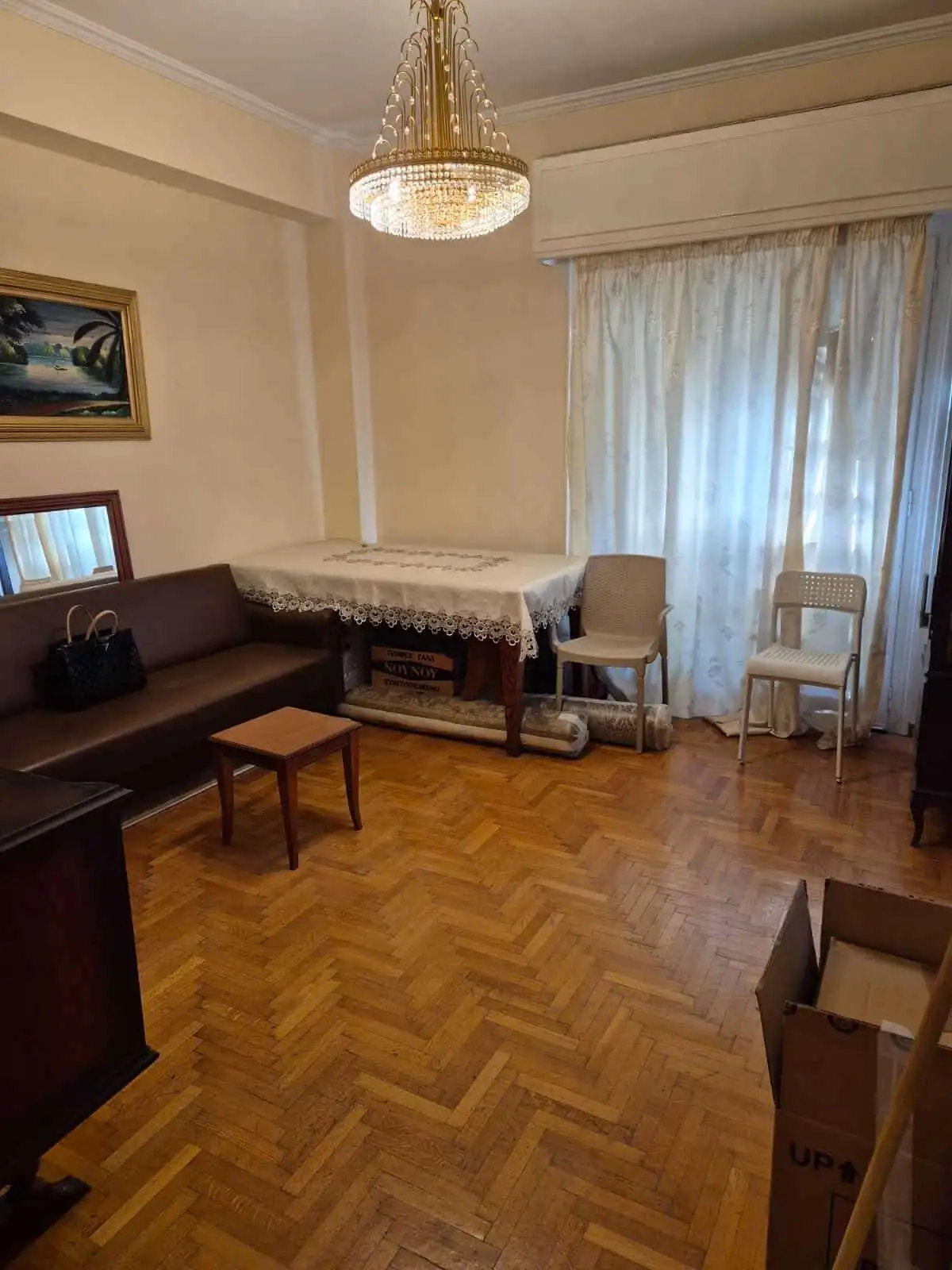 Bright living room in Athens apartment with wooden flooring and classic furniture.
