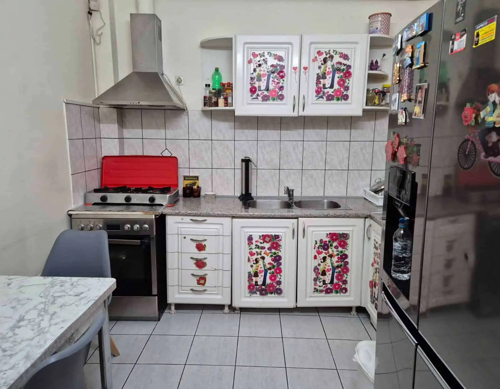 Kitchen with floral decorated cabinet doors and modern appliances.