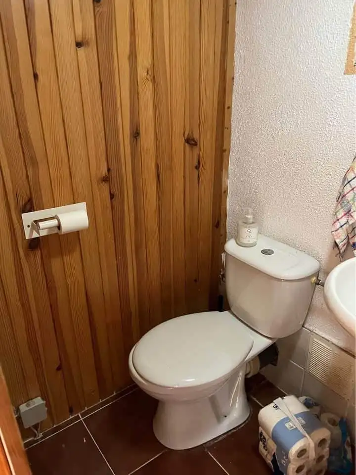 Comfortable bathroom with toilet and wooden wall paneling in a Spanish mobile home.