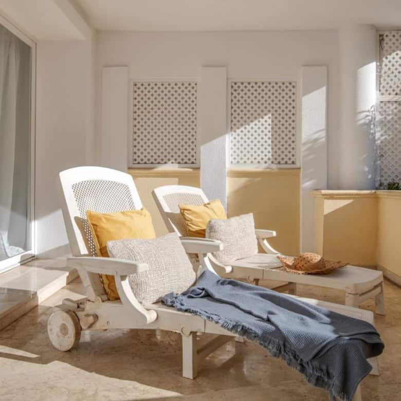 Beachfront balcony with lounge chairs and ocean view.