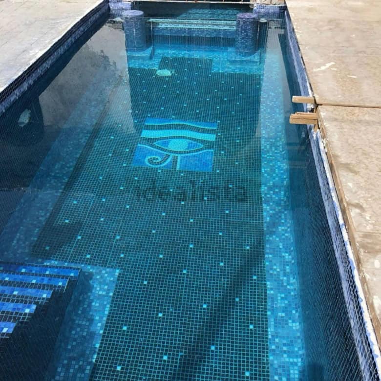 Luxury private pool in Ibiza villa estate with mosaic tiles and seating area.