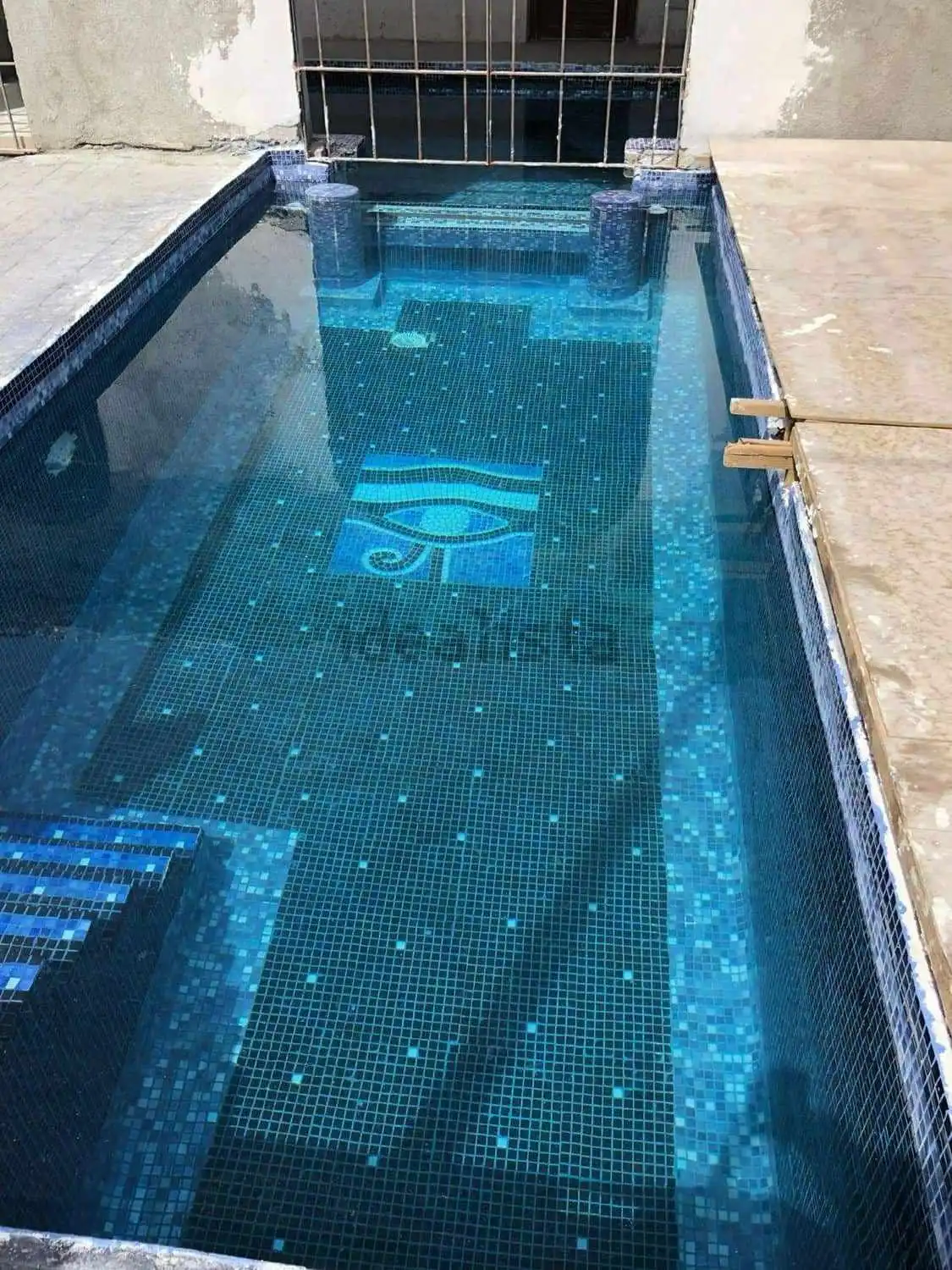 Luxury private pool in Ibiza villa estate with mosaic tiles and seating area.