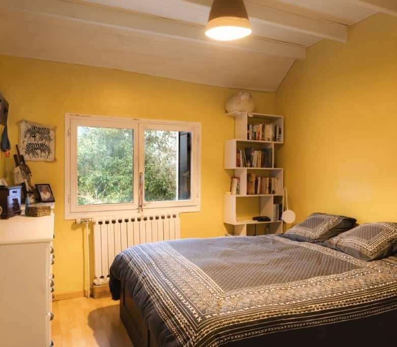 Bright bedroom with yellow walls and large window in a 6-bed estate in La Celle-sur-Morin.