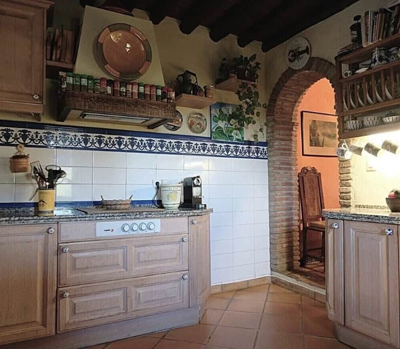Traditional rustic kitchen with wooden cabinets and brick arch in Estepona finca.