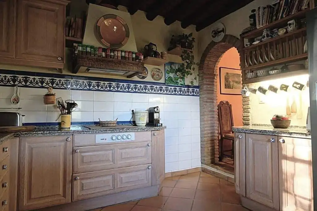 Traditional rustic kitchen with wooden cabinets and brick arch in Estepona finca.