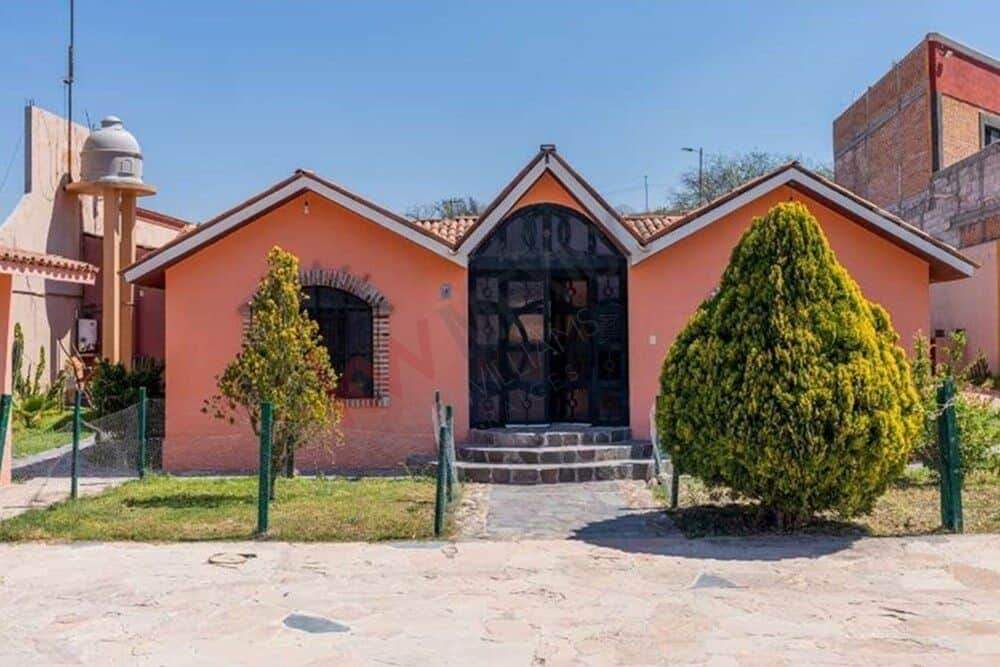 Beautiful countryside retreat featuring a pink house, lush greenery, and a welcoming entrance. Perfe.