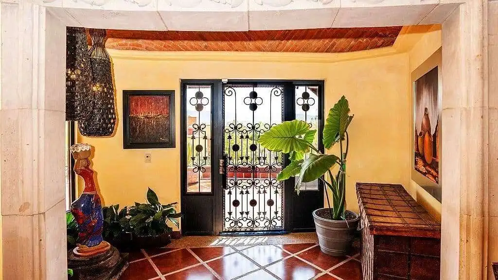 Beautiful tropical villa entrance featuring ornate wrought iron gate and lush potted plants.