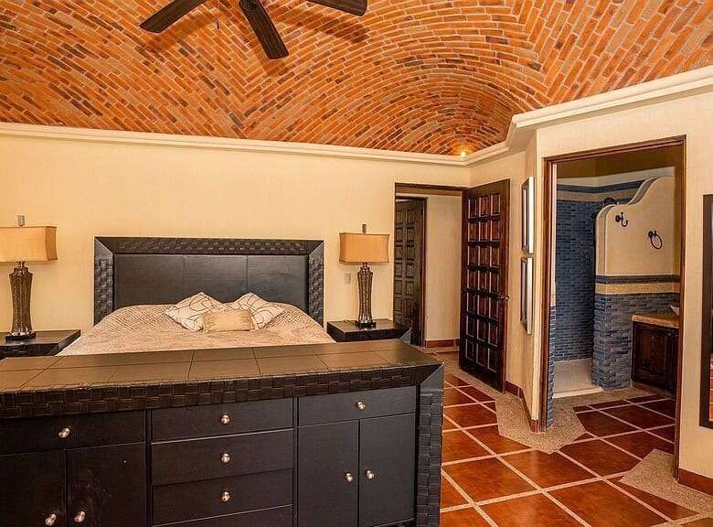 Elegant bedroom featuring a brick vaulted ceiling, modern furniture, and warm lighting.