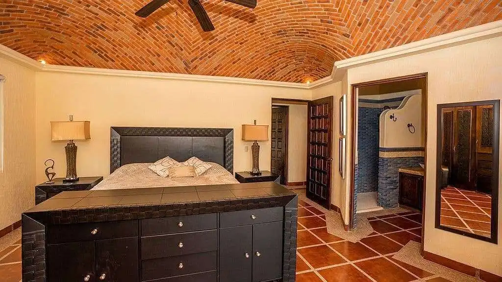 Elegant bedroom featuring a brick vaulted ceiling, modern furniture, and warm lighting.