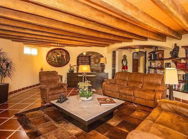 Elegant living room with rustic wooden beams and cozy leather furniture in a lakeside estate.