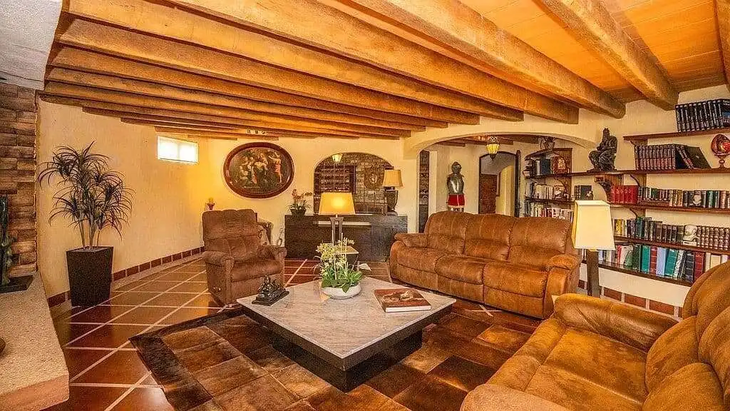 Elegant living room with rustic wooden beams and cozy leather furniture in a lakeside estate.