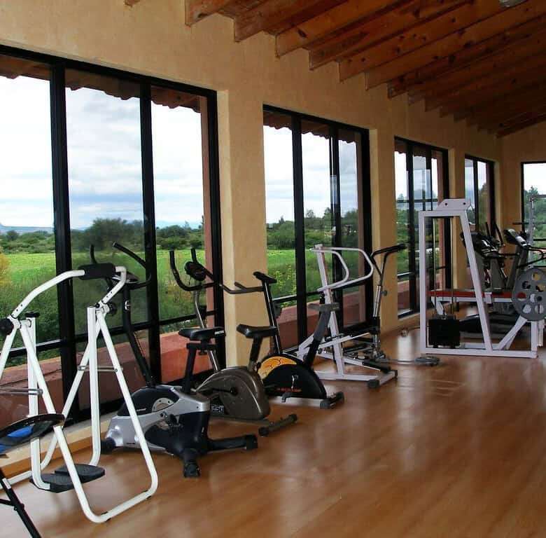 Indoor gym with exercise equipment overlooking scenic lake views.