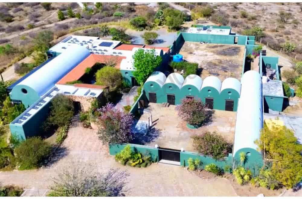 Aerial view of a distinctive desert property featuring several interconnected buildings and lush gre.