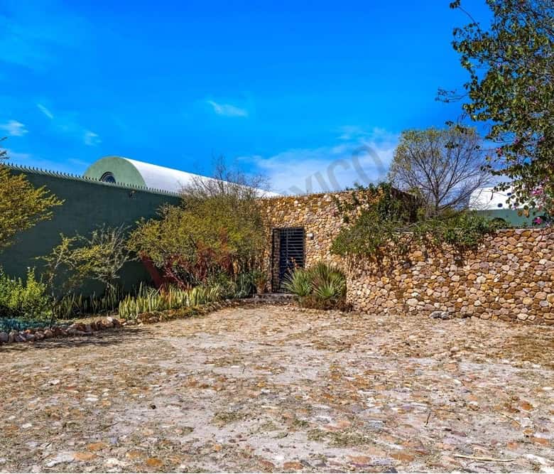 Traditional stone wall and garden in a rural setting, under a bright blue sky.