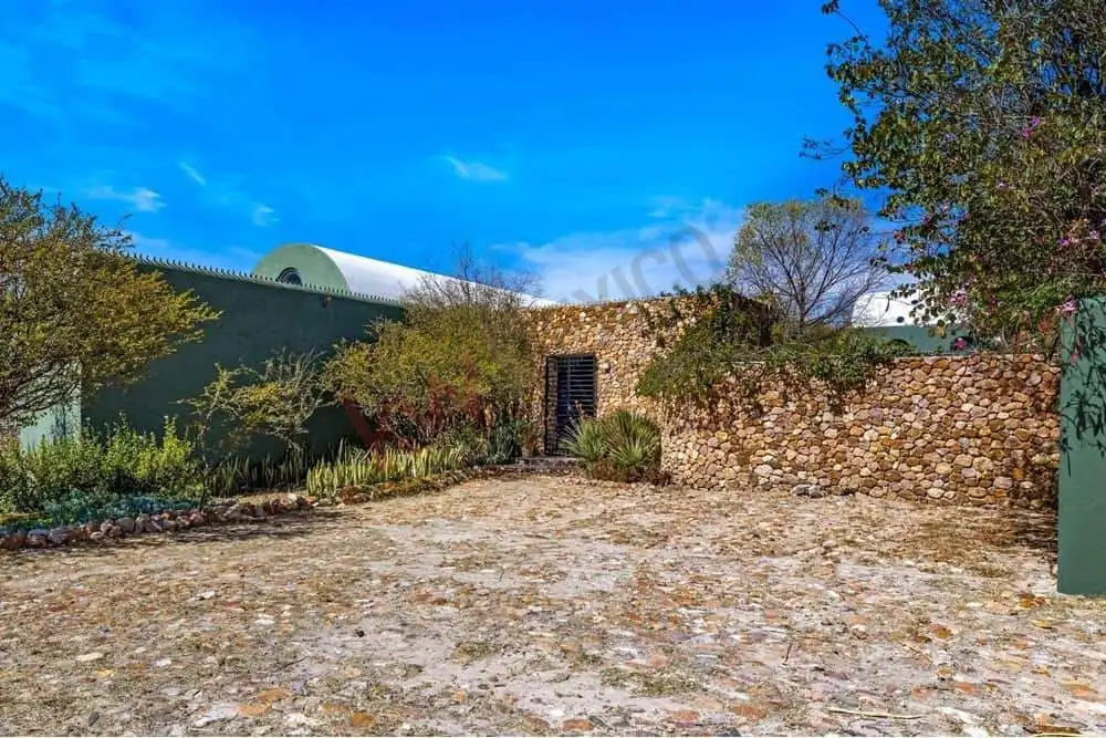 Traditional stone wall and garden in a rural setting, under a bright blue sky.