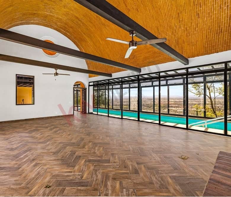 Spacious living room with floor-to-ceiling windows overlooking the pool and outdoor scenery.