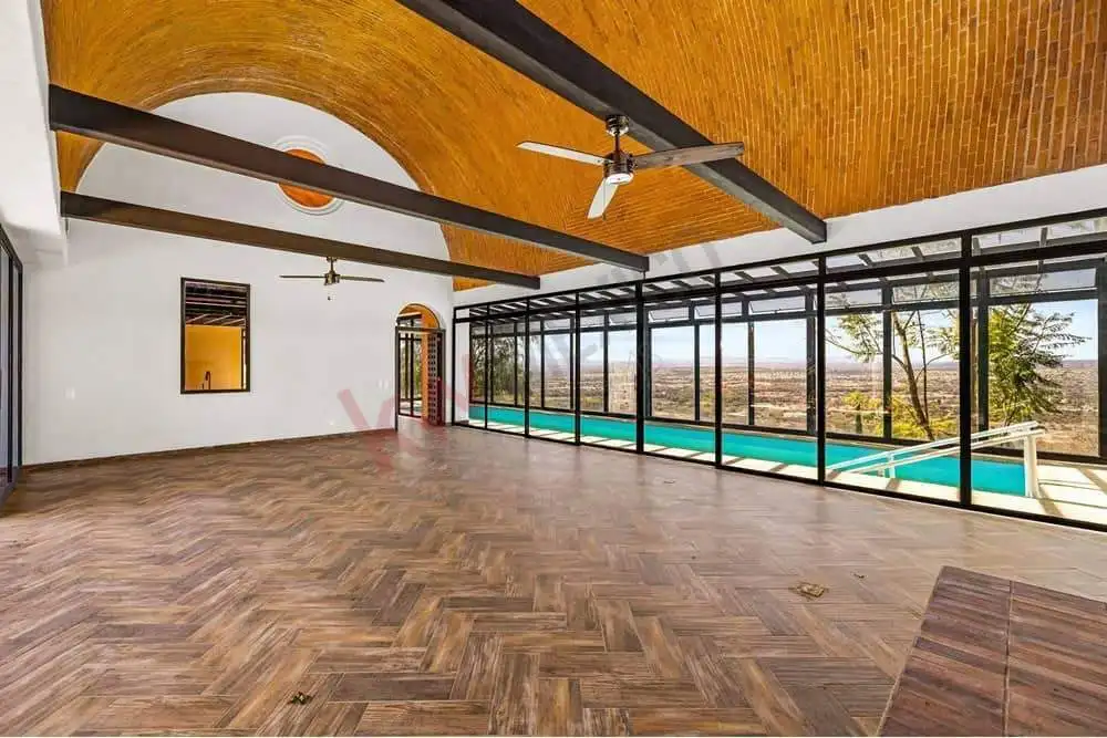 Spacious living room with floor-to-ceiling windows overlooking the pool and outdoor scenery.