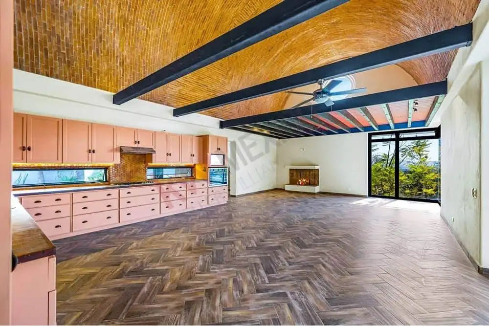 Spacious living area with high ceilings, large windows, and wooden beams, offering a bright and airy.