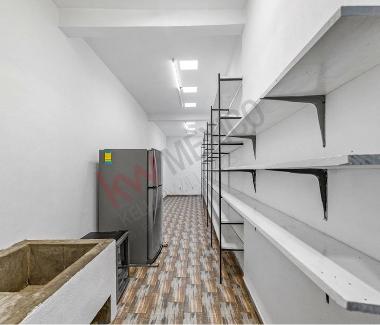 Modern kitchen with white shelves and wooden flooring for sale.