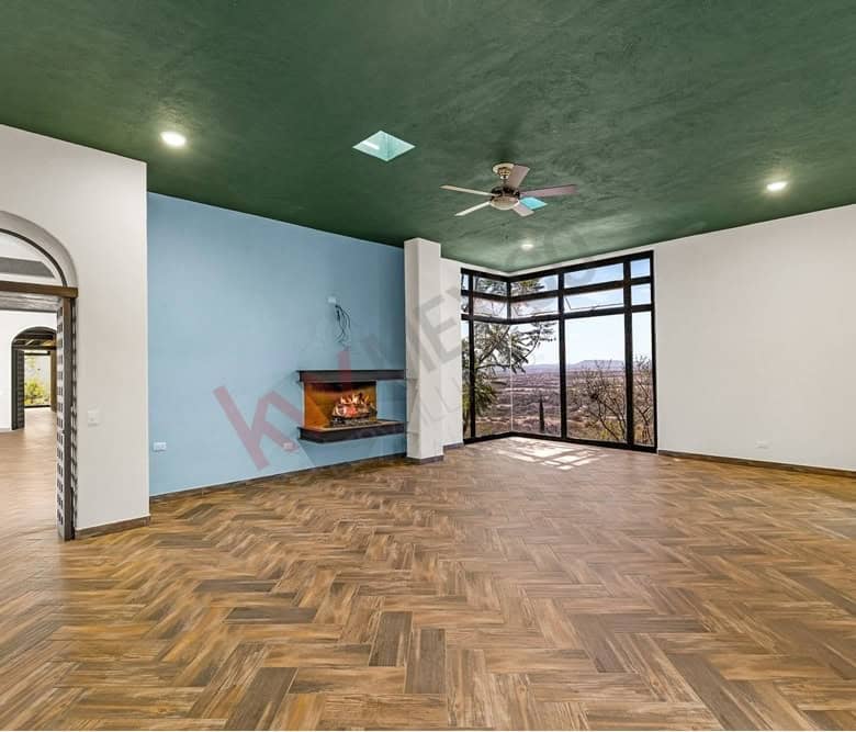 Bright living room featuring expansive windows, a cozy fireplace, and stylish wooden flooring. Perfe.