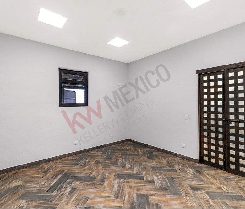 Interior room featuring a wooden floor, white walls, a small black window, and a decorative black do.