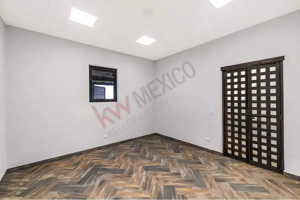Interior room featuring a wooden floor, white walls, a small black window, and a decorative black do.