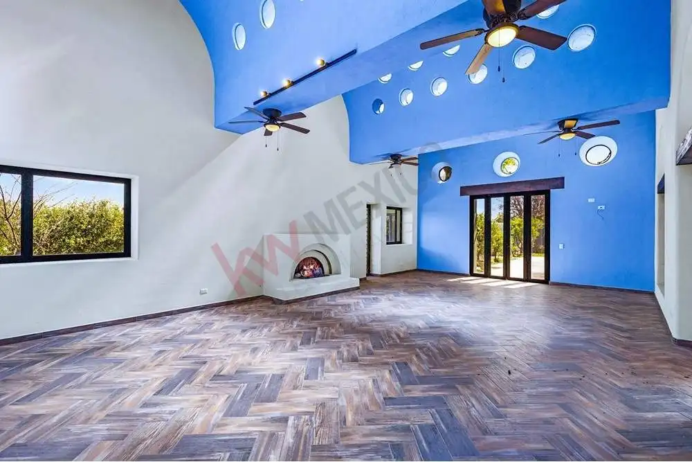 Spacious living room with vibrant blue ceiling, modern fans, and large windows in a luxury ranch est.