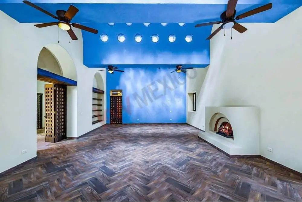 Modern living room featuring a vibrant blue ceiling, ceiling fans, and a cozy fireplace for comforta.
