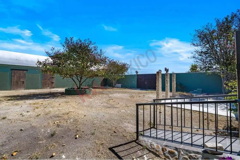 Large backyard with mature trees, a blue sky, and a secure fence, ideal for outdoor activities and f.