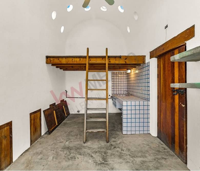 Cozy studio with wooden accents, loft area, and unique circular window design.