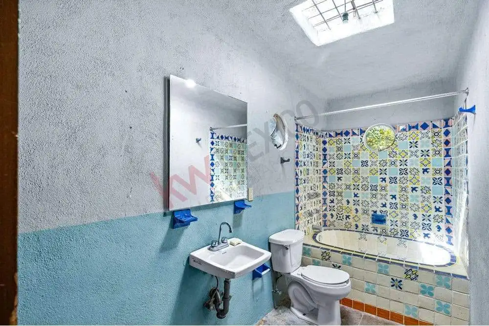 Bathroom with bathtub, sink, and toilet featuring vibrant patterned tiles.
