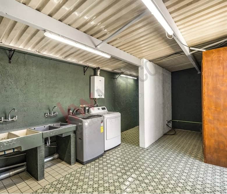 Laundry room with washing machine and utility sink in a residential property.