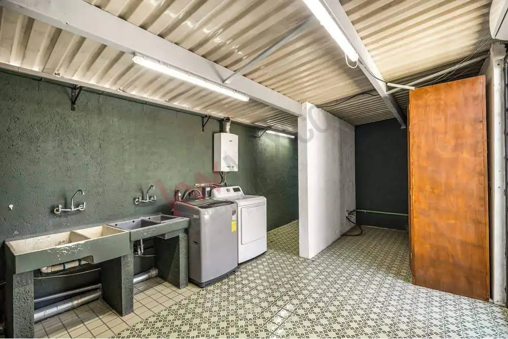Laundry room with washing machine and utility sink in a residential property.