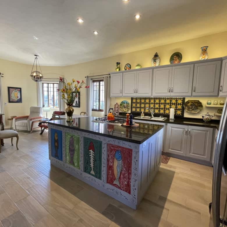 Bright kitchen featuring a vibrant, artistic island and stylish decor elements.