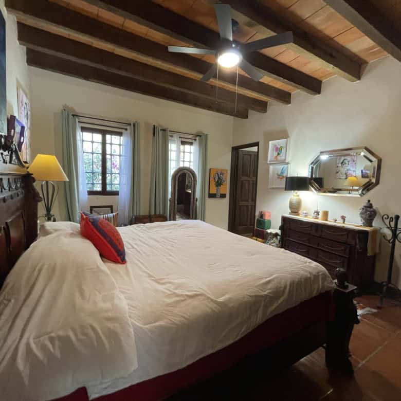 Charming bedroom with wooden ceiling, vintage furniture, and colorful decor accents.