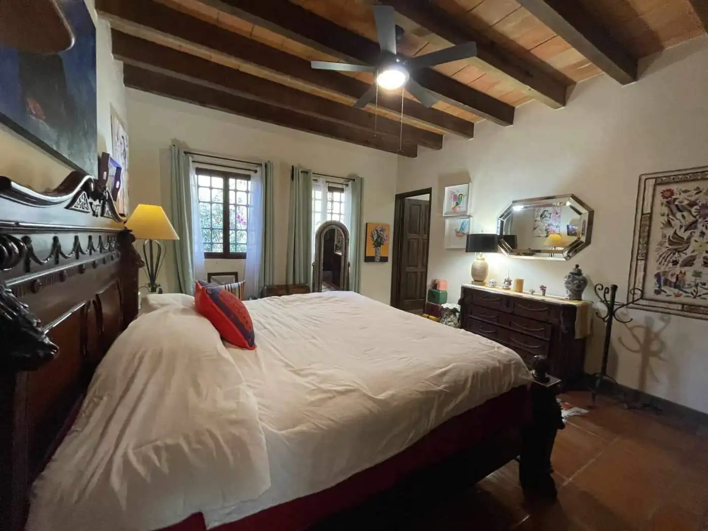 Charming bedroom with wooden ceiling, vintage furniture, and colorful decor accents.
